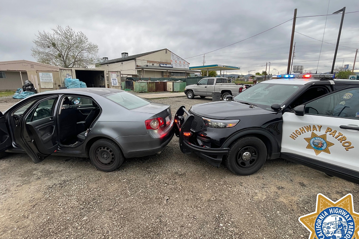 Two damaged cars after a collision, with highway patrol vehicle on scene for assistance