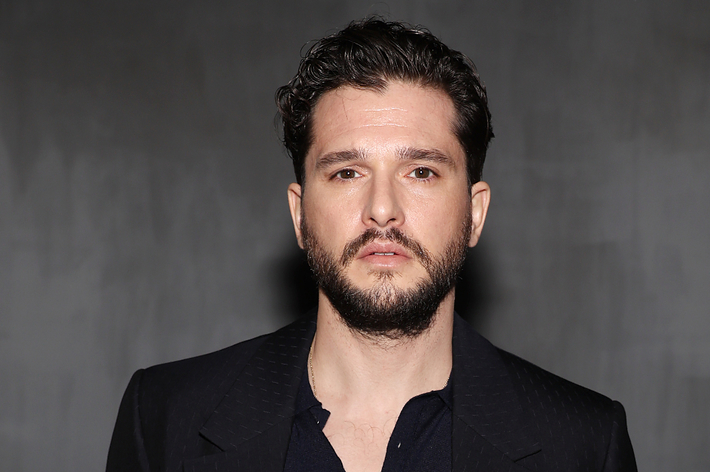 Kit Harington in a dark suit looking at the camera. Expresses a serious demeanor