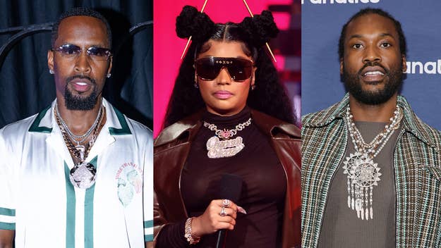 Nicki Minaj wears sunglasses and an elaborate necklace on stage, flanked by men in stylish outfits and large necklaces