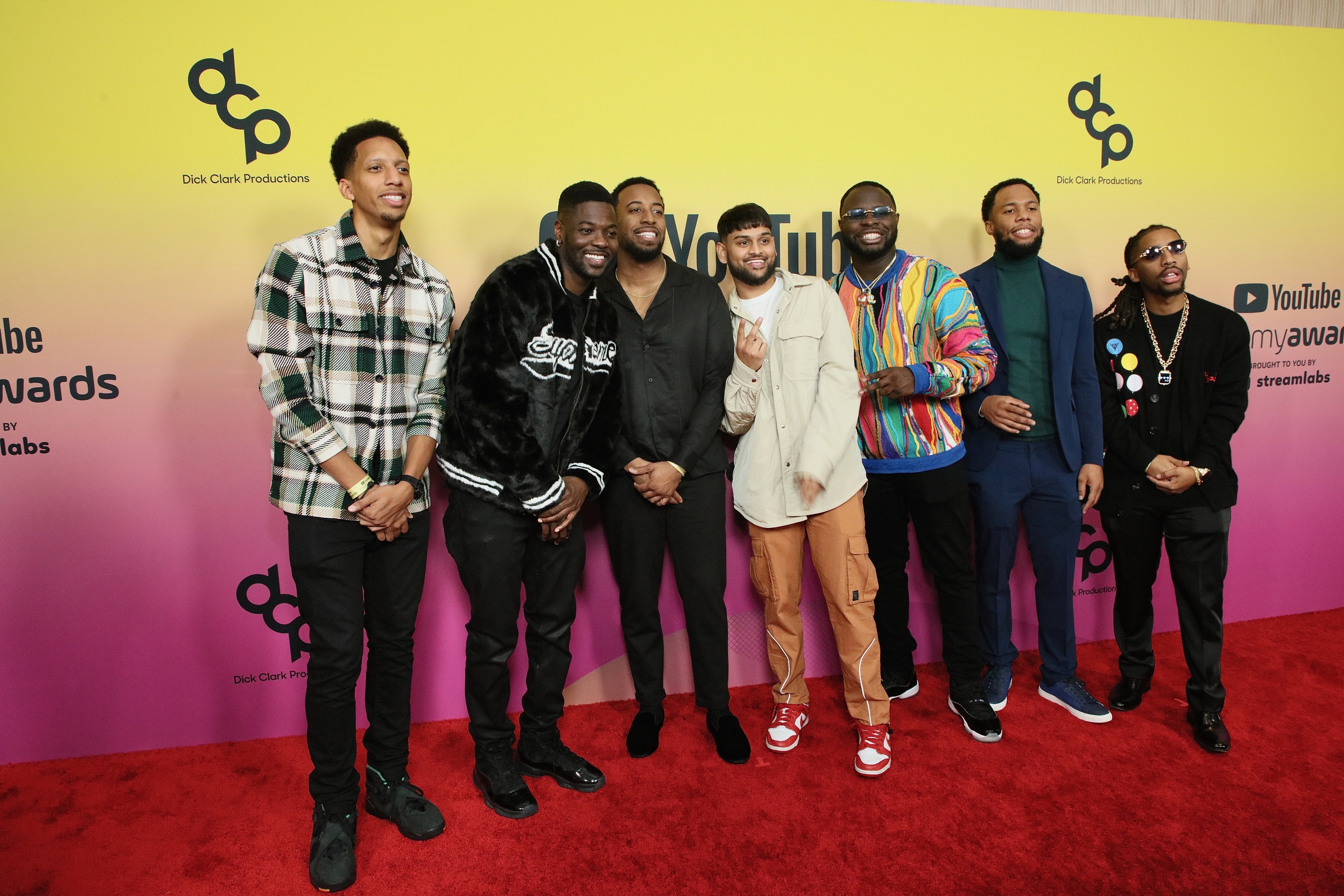 Group photo on the red carpet featuring RDCworld1 members: Mark Phillips, Desmond Johnson, Leland Manigo, Ben Skinner, Dylan Patel, Affiong Harris, and John Hill