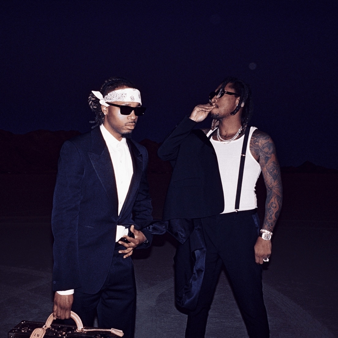 Rae Sremmurd members Slim Jxmmi and Swae Lee pose stylishly in suits; Slim Jxmmi wears a headband, Swae Lee has tattoos on his arm and holds his jacket